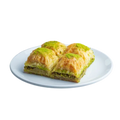 Baklava-Stücke mit besonders dicker Schicht gemahlener grüner Pistazien auf weißem Teller