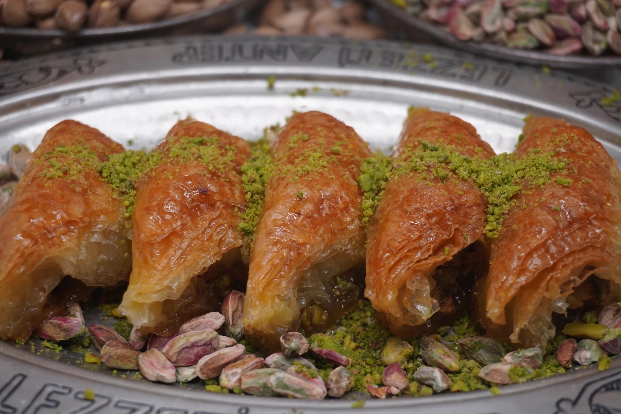 Fıstık Burma – gedrehte Baklava-Rollen mit Pistazien, in einer Reihe angerichtet