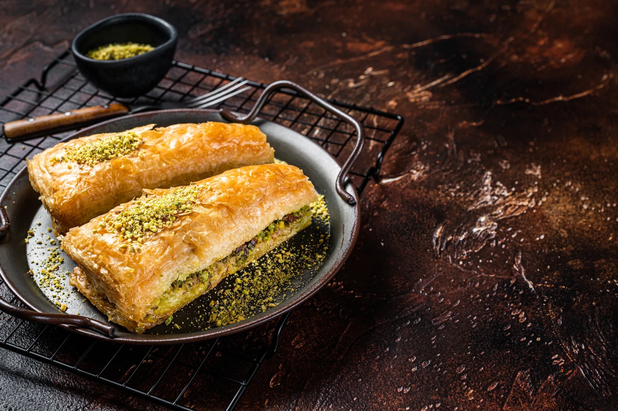 Walnuss-Baklava mit goldbraunem Blätterteig und grober Walnussfüllung in dunkler Pfanne