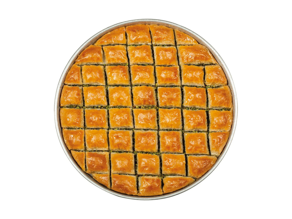 Klassisches Pistazien-Baklava im runden Blech, in Rauten geschnitten, mit grüner Antep-Pistazienschicht