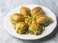 Midye Baklava – muschelförmige Stücke mit gefächertem Blätterteig und ganzen Pistazien auf weißem Teller